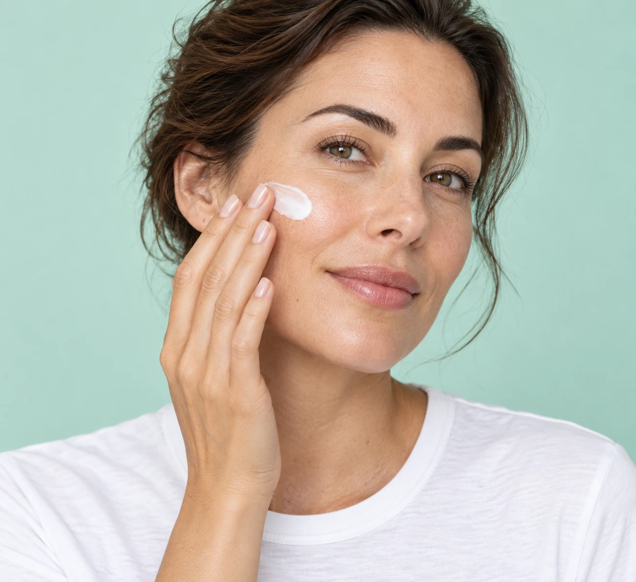 Une femme adulte applique une touche de crème sur sa joue